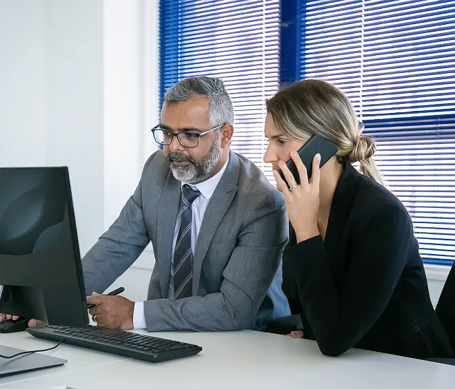 focused-business-colleagues-working-together-sitting-workplace-speaking-cellphone-using-computer-teamwork-communication-concept